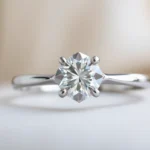 A woman admiring her 1 carat diamond engagement ring with a sparkling center stone and delicate